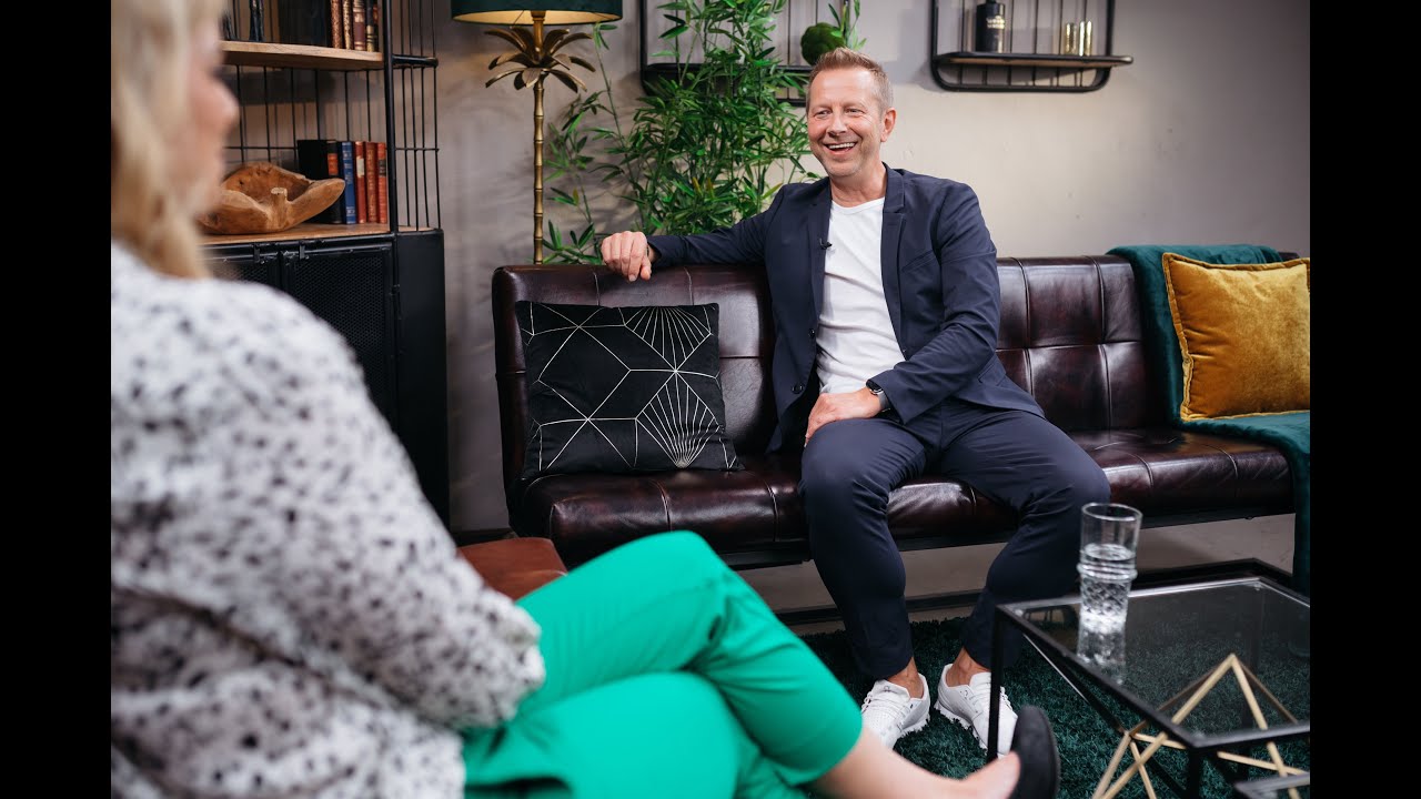 Rainer Stolte lacht auf dem Studiosofa von Hauptstadt.TV im Gespräch mit Moderatorin Alissa Stein